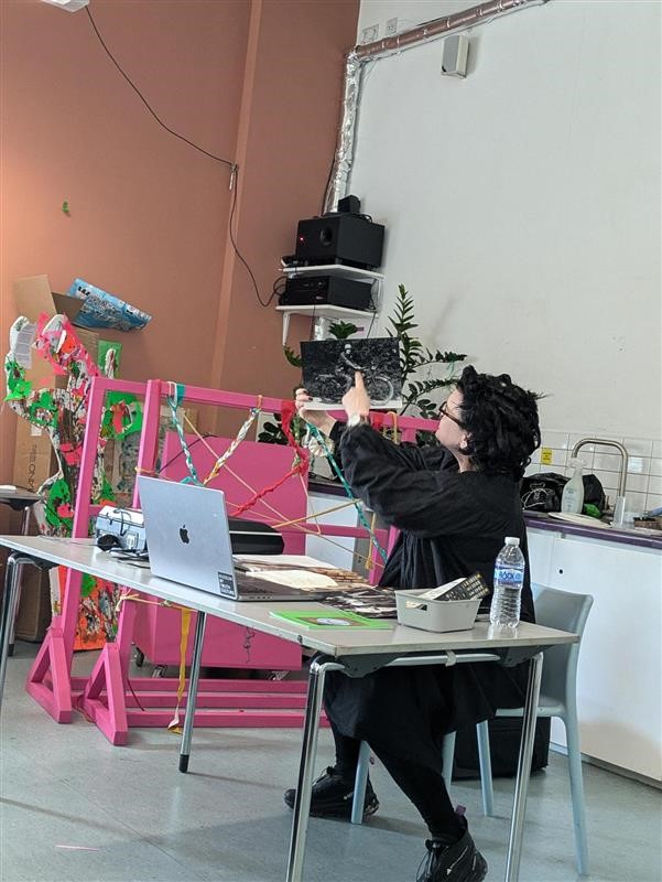 A photo of Ann showing students artefacts from the Museum. She is holding up a black and white photo of a woman riding a motorcycle