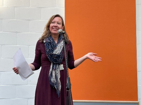 Deputy Pro Vice Chancellor Kelly Coate in front of an orange and white wall.